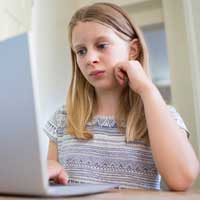 kleines Mädchen schaut auf Laptop