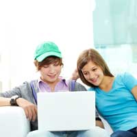 Zwei Teenager sitzen zusammen vor einem Laptop
